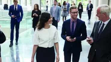 Group of people walking in a modern office hallway.