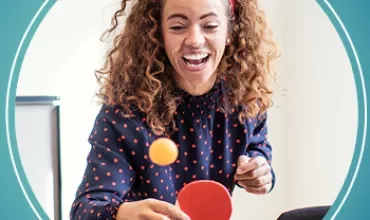 Person playing table tennis, smiling and focused.